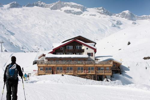 a man on skis in front of a ski lodge at Hamilton Lodge & Spa in Belalp