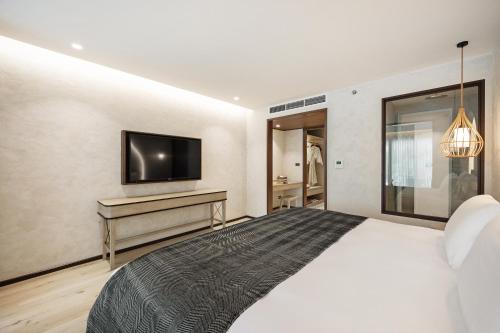 a bedroom with a bed and a tv on a wall at VALA Hua Hin - Nu Chapter Hotels in Cha Am