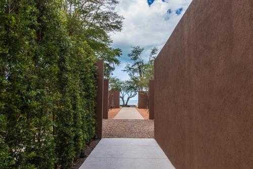 a walkway between two hedges with trees in the distance at VALA Hua Hin - Nu Chapter Hotels in Cha Am