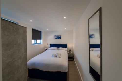 a bedroom with a large white bed and a mirror at 16 Queen Avenue City Centre Serviced Apartment w free parking in Liverpool