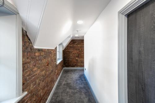 a hallway with a brick wall and a window at 16 Queen Avenue Collection by Happy Days in Liverpool