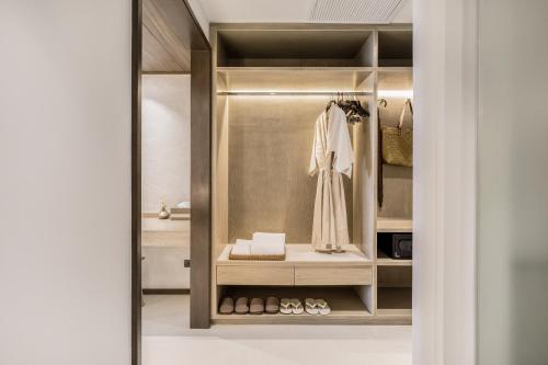 a walk in closet with a robe and shoes at VALA Hua Hin - Nu Chapter Hotels in Cha Am