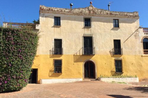 a yellow building with a hedge in front of it at B&B Can Casadella in Premia de Dalt