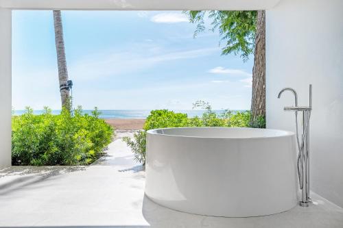 a bath tub with a view of the beach at VALA Hua Hin - Nu Chapter Hotels in Cha Am
