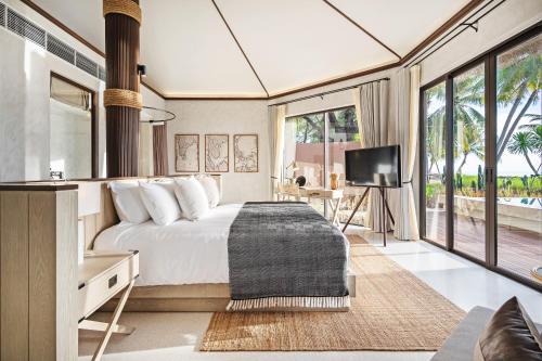 a bedroom with a bed and a tv in a room at VALA Hua Hin - Nu Chapter Hotels in Cha Am