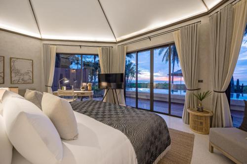 a bedroom with a large bed and a large window at VALA Hua Hin - Nu Chapter Hotels in Cha Am
