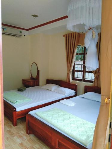 a bedroom with two beds and a dress hanging from a window at Ba Be Lake View Homestay in An Ma
