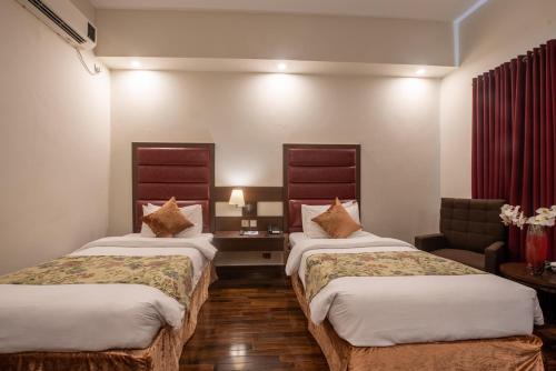 a hotel room with two beds and a couch at Legend Hotel Islamabad in Islamabad