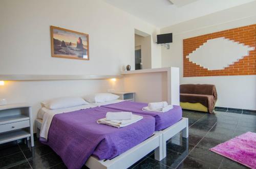 Skala Sunset Hotel and spa في إيوس خورا: غرفة نوم مع سرير أرجواني وأريكة