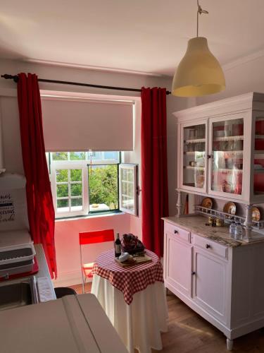 a kitchen with red curtains and a table in it at Casa Morgado do Casco in Estremoz