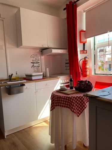 a kitchen with white cabinets and a table with a red curtain at Casa Morgado do Casco in Estremoz