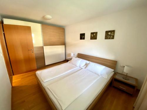 1 dormitorio con 1 cama blanca grande y suelo de madera en Ferienwohnungen Christine en Dornbirn