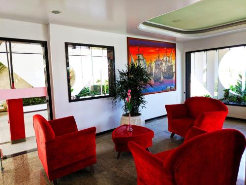 a waiting room with red chairs and a table and windows at Hotel Portal De Eunápolis in Eunápolis