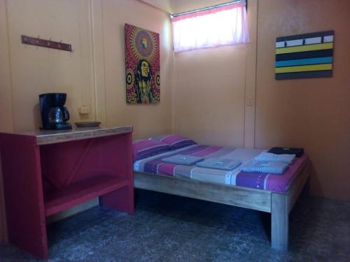 a small bedroom with a bed and a window at Hotel One Love Puerto Viejo in Puerto Viejo