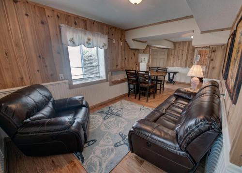 a living room with two leather couches and a table at Outer Banks Motel - Village Accommodations in Buxton