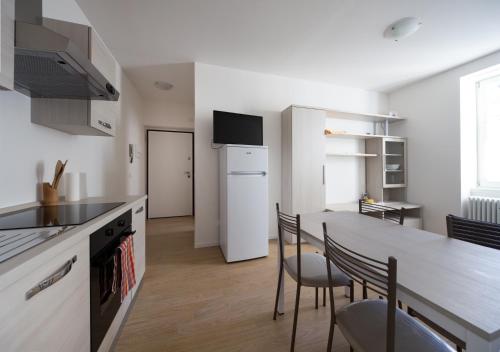 una cucina con tavolo, sedie e frigorifero bianco di I Dodici mesi - appartamento Primavera a Trento