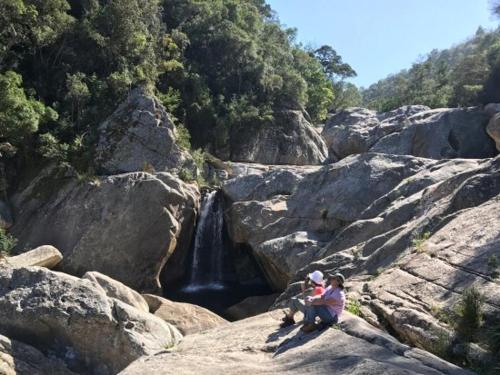 two people sitting on rocks in front of a waterfall at Nature on your doorstep in Hoekwil