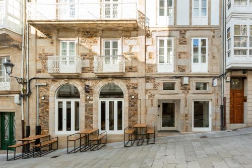 un edificio con mesas y sillas delante de él en Hostal Pórtico, en Betanzos