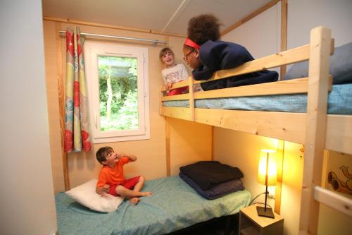 - un enfant assis sur un oreiller dans un lit superposé dans l'établissement Camping Le Val de Trie, à Béhen