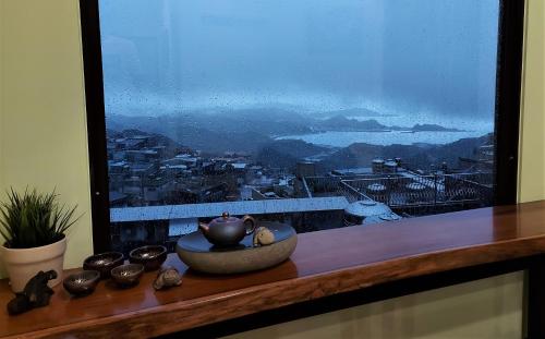 a bowl on a table with a large window at Dosun B&B in Jiufen