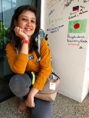 a woman sitting in front of a refrigerator at Beds In Garden Hostel in Ipoh