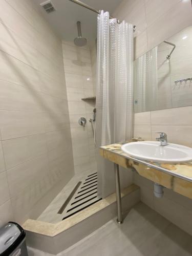 uma casa de banho com um lavatório e um chuveiro em Maro Hotel em Sochi