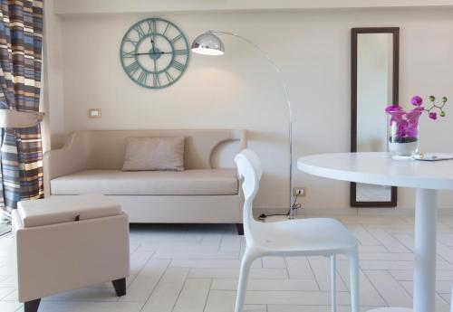 a white living room with a table and a clock at Nero D'Avorio Aparthotel & SPA in Rimini
