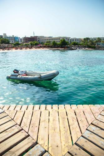 a boat sitting on the water next to a dock at Redcon Suites in Hurghada