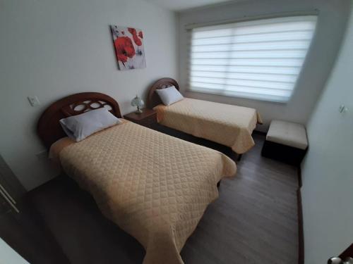 a small room with two beds and a window at Moderno departamento en Condominio Providencia in Cuenca
