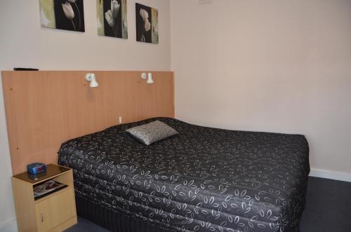 a small bedroom with a bed and a night stand at Clifton Motel in Albury
