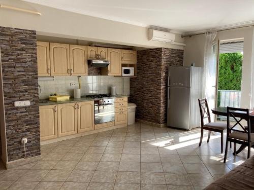 eine Küche mit Holzschränken, einem Tisch und einem Kühlschrank in der Unterkunft Kristály Apartman in Eger