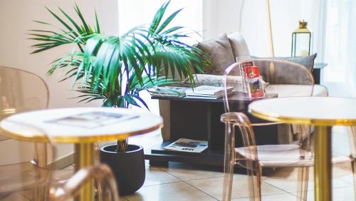 un soggiorno con 2 tavoli e una pianta in vaso di Hotel Venini a Milano