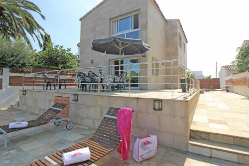 un edificio con sillas y una sombrilla en un patio en Apart-rent Villa Ter 0031, en Empuriabrava