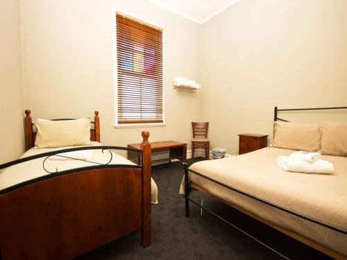 a room with two beds and a table and a window at Peden's Hotel in Cessnock