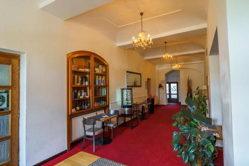 sala de estar con alfombra roja, mesas y sillas en Hotel U Labutě, en Žďár nad Sázavou