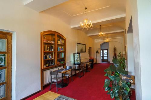 a living room with a red carpet and tables and chairs at Hotel U Labutě in Žďár nad Sázavou