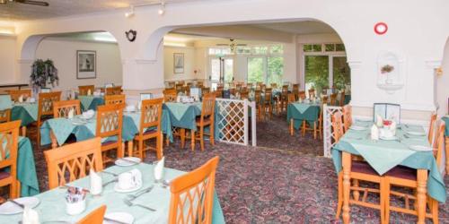 a dining room with tables and chairs with blue tablecloths at The Burlington Hotel in Torquay