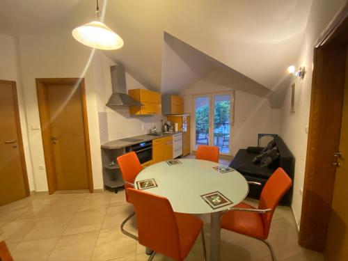 a kitchen and dining room with a table and orange chairs at Apartments Grozdana in Gradac