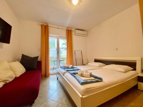 a bedroom with two beds and a red couch at Apartments Grozdana in Gradac