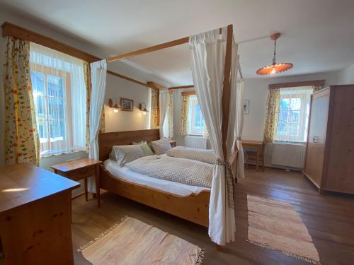a bedroom with a canopy bed and windows at Kürbishof Gartner in Fehring