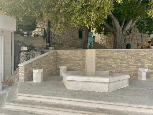 a statue in front of a brick wall with a bench at Apartments Grozdana in Gradac