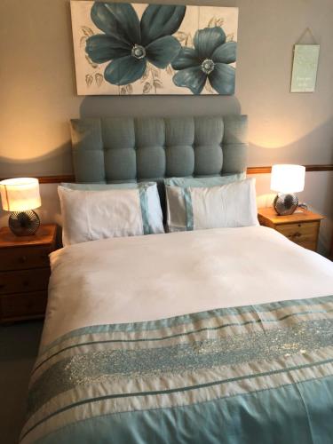 a bedroom with a large bed with two lamps at Love & Peace in Orpington