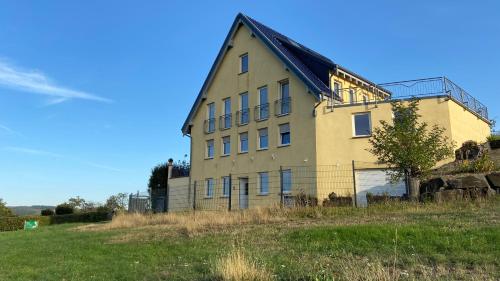 a large building on a hill with a grass field at Roosartige Ferien - Ferienwohnung im Hanswieschen - Oberwesel Bacharach in Langscheid
