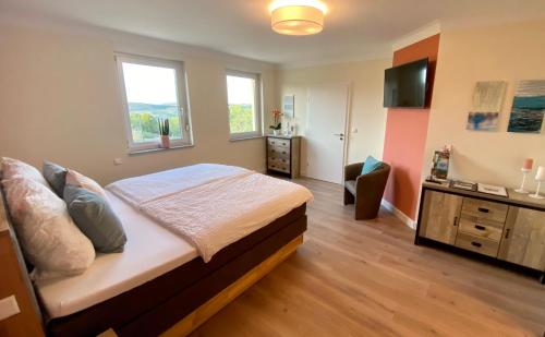 a bedroom with a bed and a dresser and two windows at Roosartige Ferien - Ferienwohnung im Hanswieschen - Oberwesel Bacharach in Langscheid
