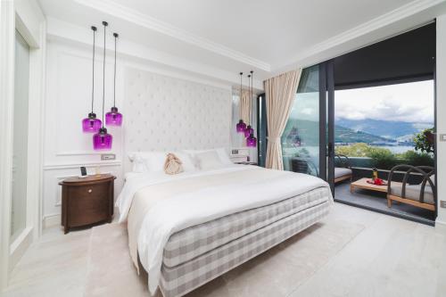 a bedroom with a large bed and a large window at Boutique Hotel Vissi d'Arte in Budva