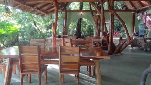 um restaurante com mesas e cadeiras de madeira e árvores em Nosara Sunrise Bed and Breakfast em Nosara