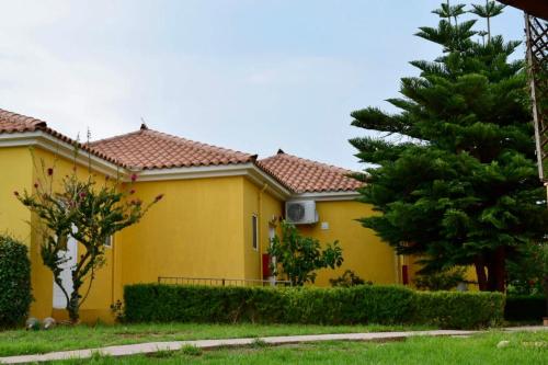 a yellow house with a tree in front of it at Boutique Hotel Ileas Village in Arkoudi