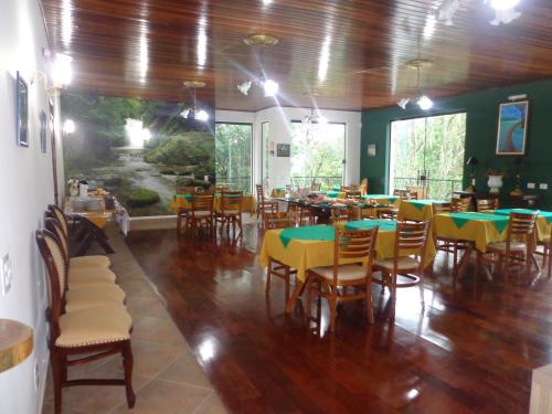 a dining room with tables and chairs with green and yellow tables at Golden Forest Pousada in Campos do Jordão