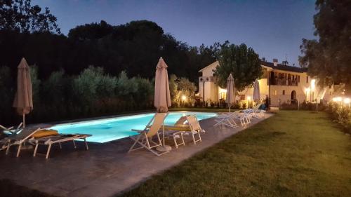 a pool with chairs and umbrellas in front of a house at Punta dei Lecci in Riparbella
