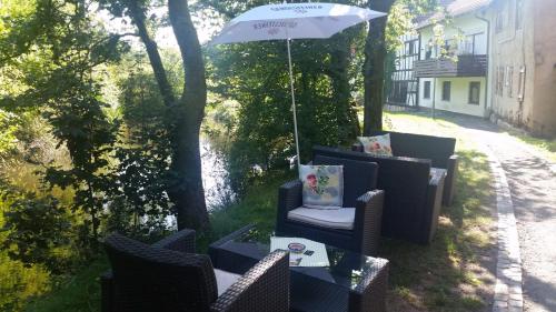 a patio with chairs and an umbrella and water at Lenzenhof anno 1720 II in Schotten